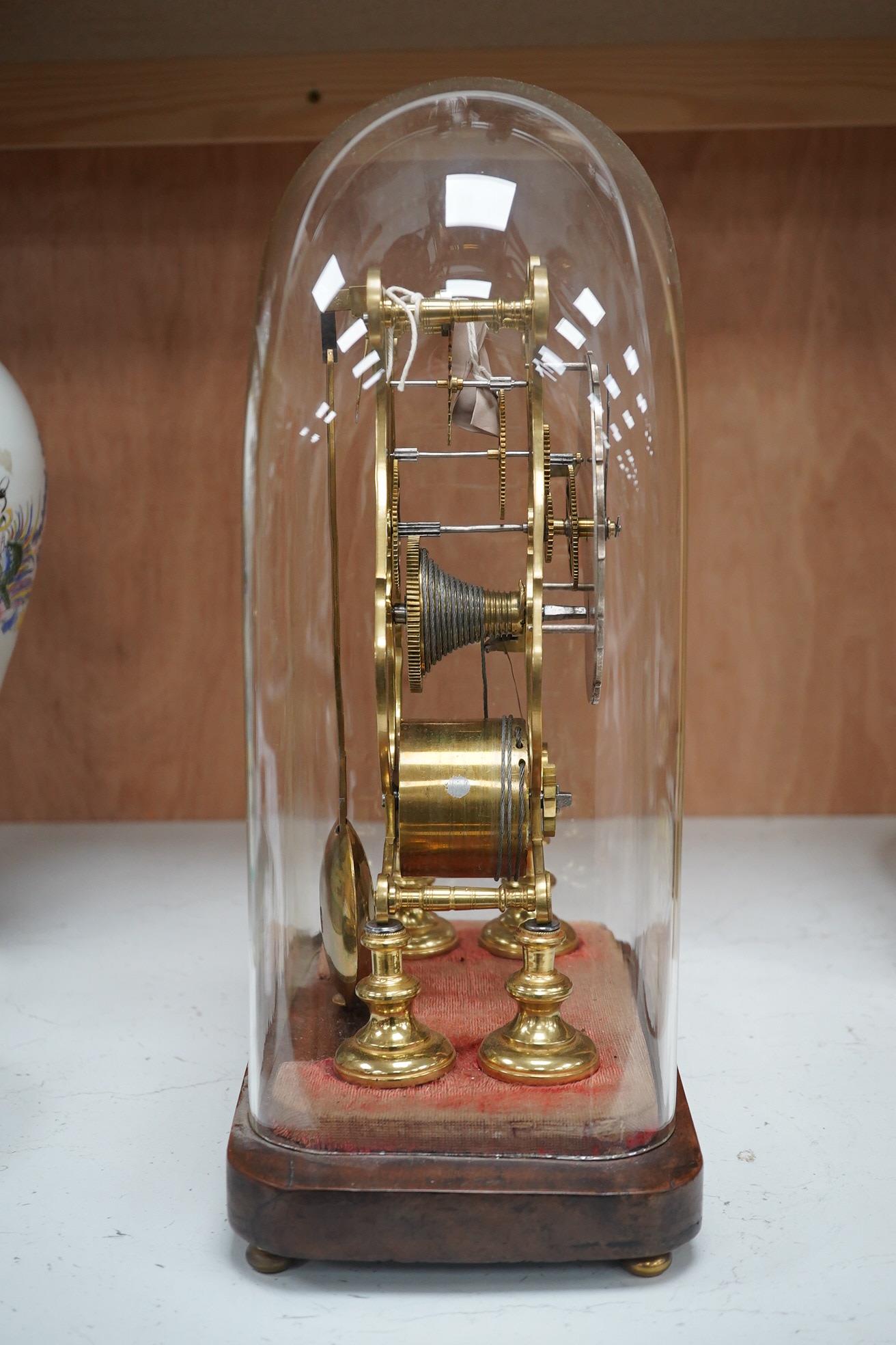 A late 19th century brass skeleton timepiece, the silvered chapter ring with Roman numerals, on a stand, under a glass dome, 37cm high. Condition - pendulum adjustment needed